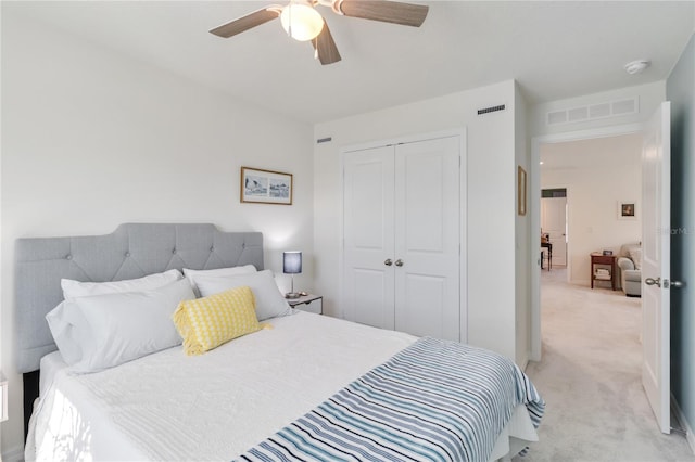 bedroom with a closet, visible vents, light colored carpet, and a ceiling fan