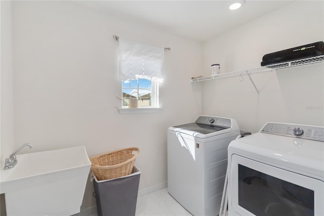 clothes washing area with marble finish floor, washer and clothes dryer, a sink, baseboards, and laundry area