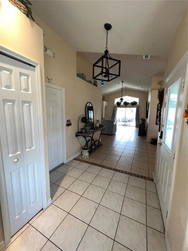 hall featuring visible vents, baseboards, an inviting chandelier, light tile patterned floors, and lofted ceiling