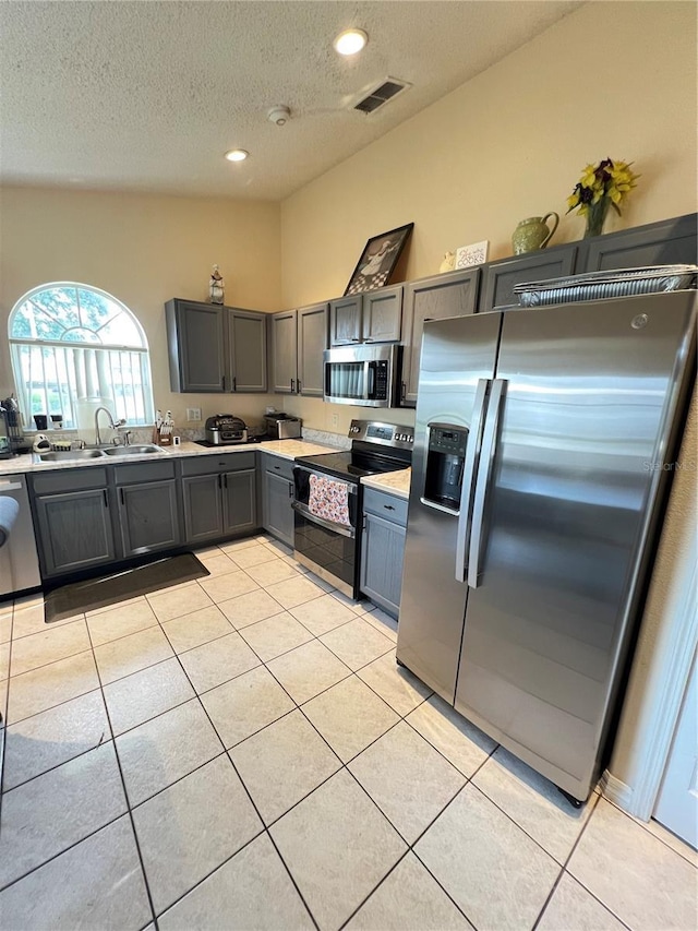 kitchen with visible vents, gray cabinets, appliances with stainless steel finishes, and a sink