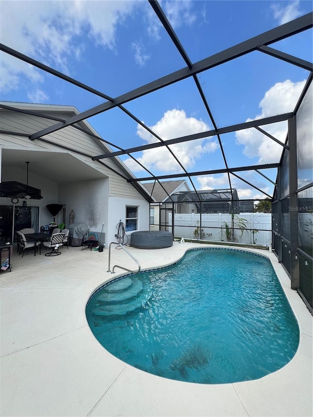 view of swimming pool featuring a patio area, glass enclosure, a fenced in pool, and fence