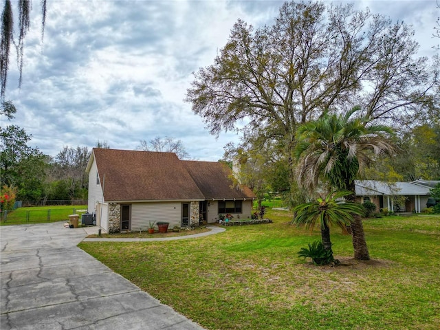 view of front facade featuring a garage, concrete driveway, a front lawn, and fence