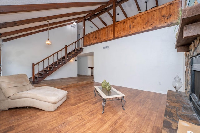 living area featuring visible vents, stairway, a stone fireplace, and wood finished floors