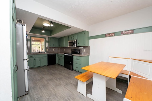 kitchen featuring freestanding refrigerator, stainless steel microwave, green cabinets, and electric range oven