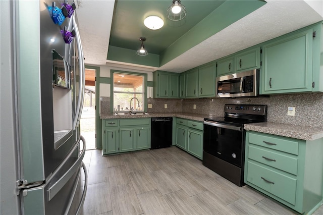 kitchen with a sink, tasteful backsplash, appliances with stainless steel finishes, green cabinetry, and a raised ceiling