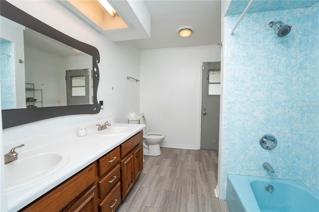 bathroom with a sink, shower / bath combination, toilet, and double vanity