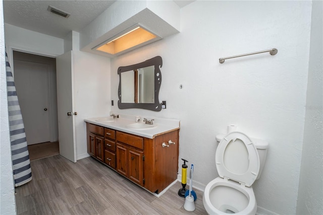 full bath featuring visible vents, toilet, wood finished floors, and a sink