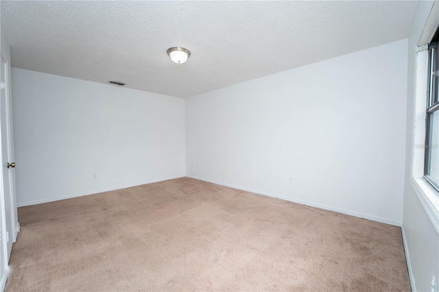 carpeted empty room featuring visible vents, a textured ceiling, and baseboards