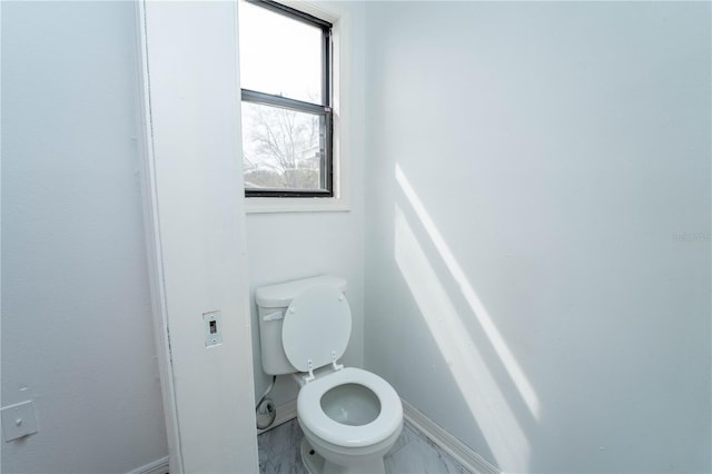 bathroom featuring marble finish floor, toilet, and baseboards