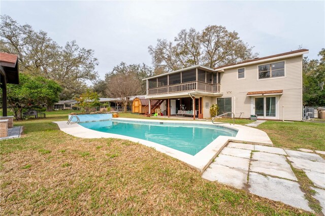 back of house featuring stairway, an outdoor pool, a sunroom, a patio area, and a lawn