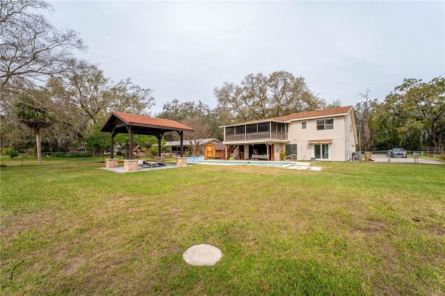 back of property with fence, a yard, an outdoor pool, a gazebo, and a patio area