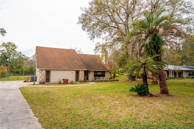 view of front of house featuring central air condition unit, concrete driveway, a front lawn, and fence