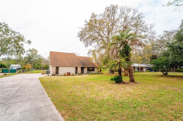 view of front of property with a front yard, concrete driveway, and fence