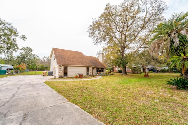 view of front of home featuring a front yard, a chimney, driveway, and fence