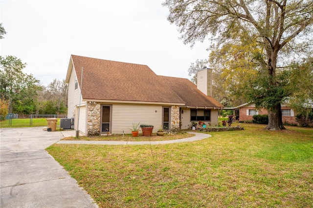 view of front of house with a front yard, cooling unit, fence, driveway, and a chimney