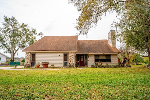 view of front of house featuring roof with shingles, a chimney, and a front yard