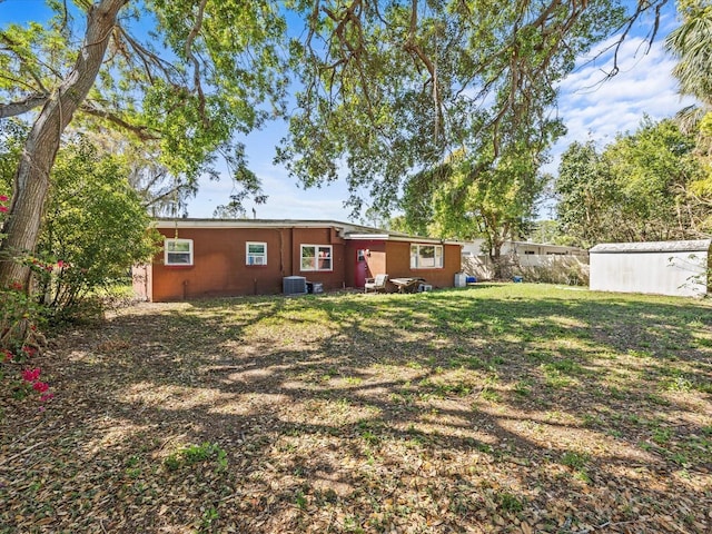 back of property featuring central AC unit and a lawn