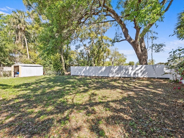 view of yard featuring an outdoor structure, a storage unit, and fence