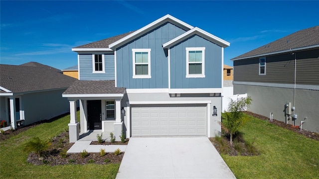 view of front of home featuring driveway, board and batten siding, roof with shingles, a front yard, and an attached garage