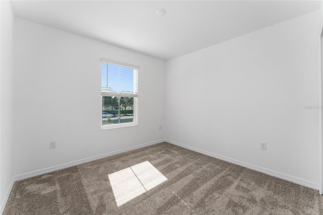 carpeted empty room featuring baseboards