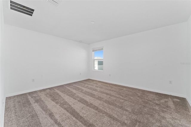 spare room with visible vents, baseboards, and carpet flooring