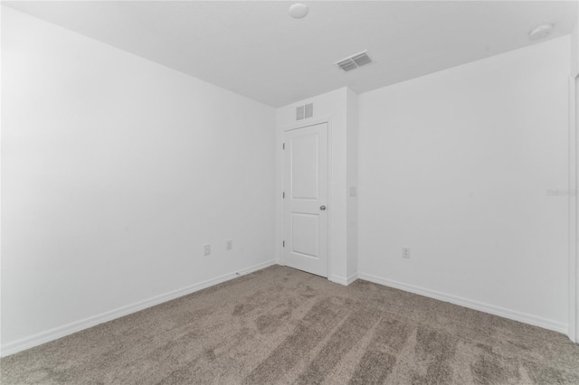 carpeted spare room featuring visible vents and baseboards