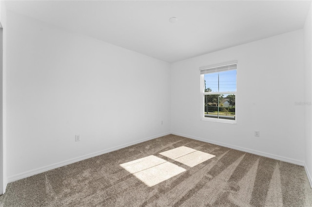 carpeted empty room featuring baseboards