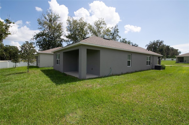 rear view of house featuring a patio area, stucco siding, cooling unit, and a yard