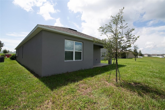 view of property exterior with stucco siding, a lawn, and a patio