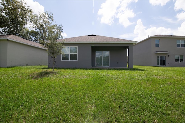 back of property featuring a lawn and stucco siding