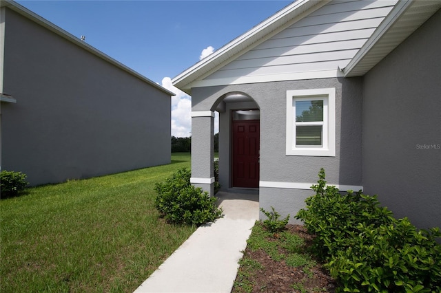 doorway to property featuring a yard and stucco siding