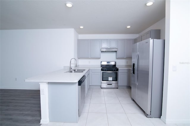 kitchen with gray cabinetry, light countertops, appliances with stainless steel finishes, a peninsula, and a sink