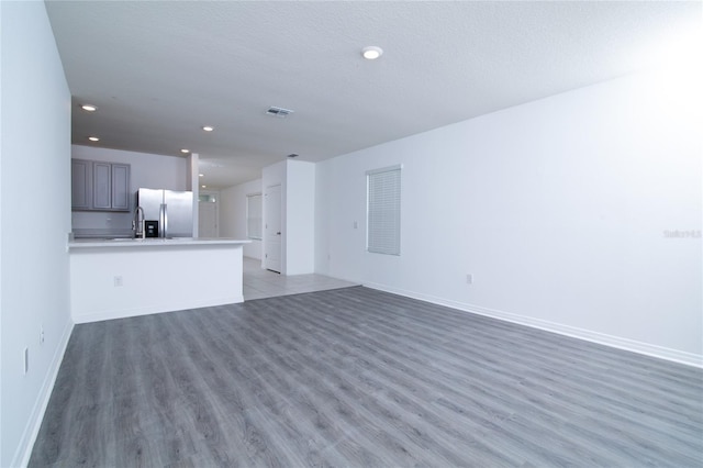 unfurnished living room with recessed lighting, baseboards, light wood-type flooring, and a textured ceiling