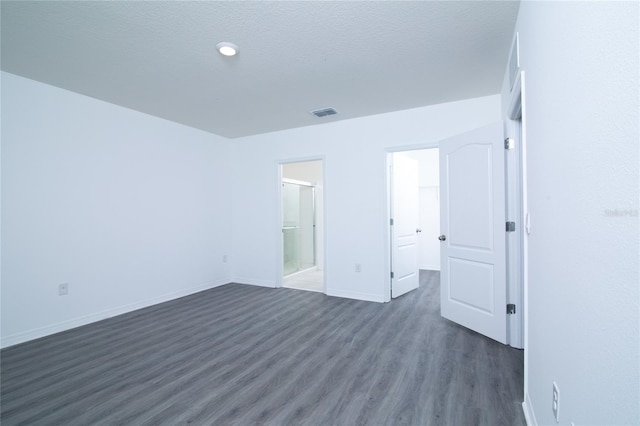 unfurnished bedroom featuring dark wood finished floors, visible vents, a textured ceiling, and baseboards