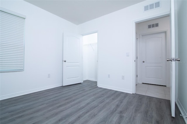 unfurnished bedroom featuring a closet, visible vents, baseboards, and wood finished floors