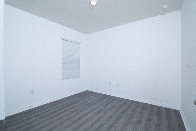 unfurnished room with baseboards, dark wood-type flooring, and a textured ceiling