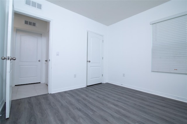 unfurnished bedroom with visible vents, baseboards, and wood finished floors