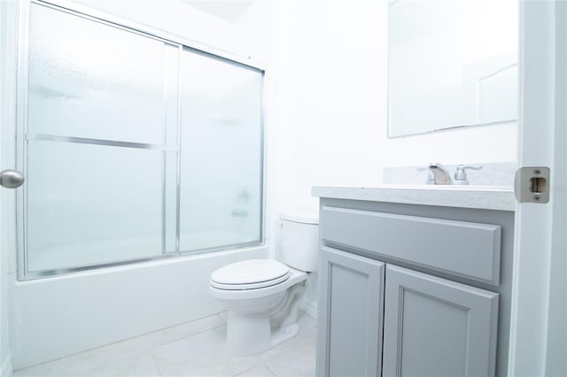 bathroom featuring tile patterned flooring, combined bath / shower with glass door, toilet, and vanity