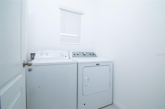 washroom featuring baseboards, separate washer and dryer, and laundry area