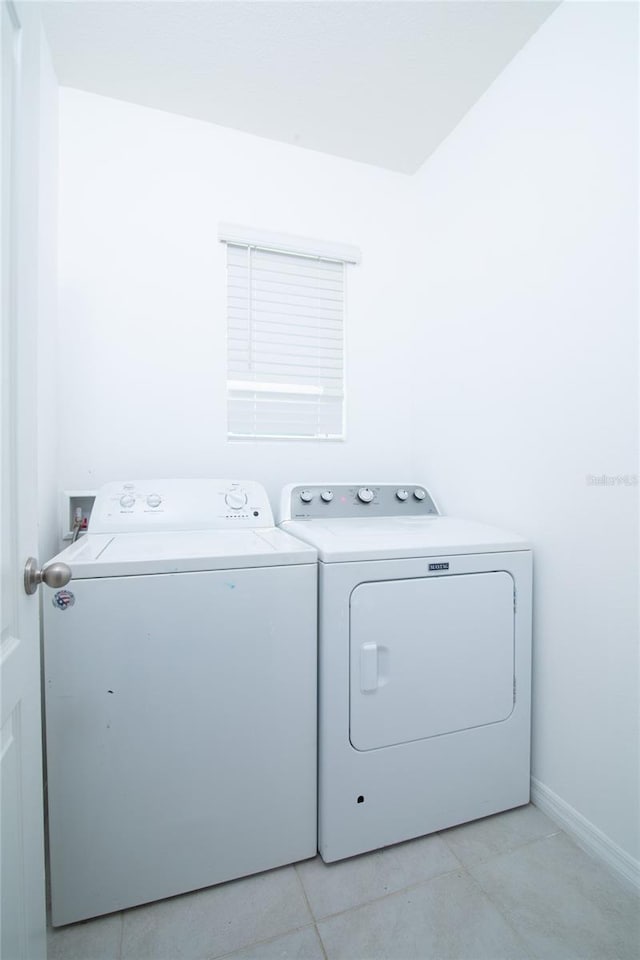 laundry area with laundry area, light tile patterned floors, washing machine and dryer, and baseboards