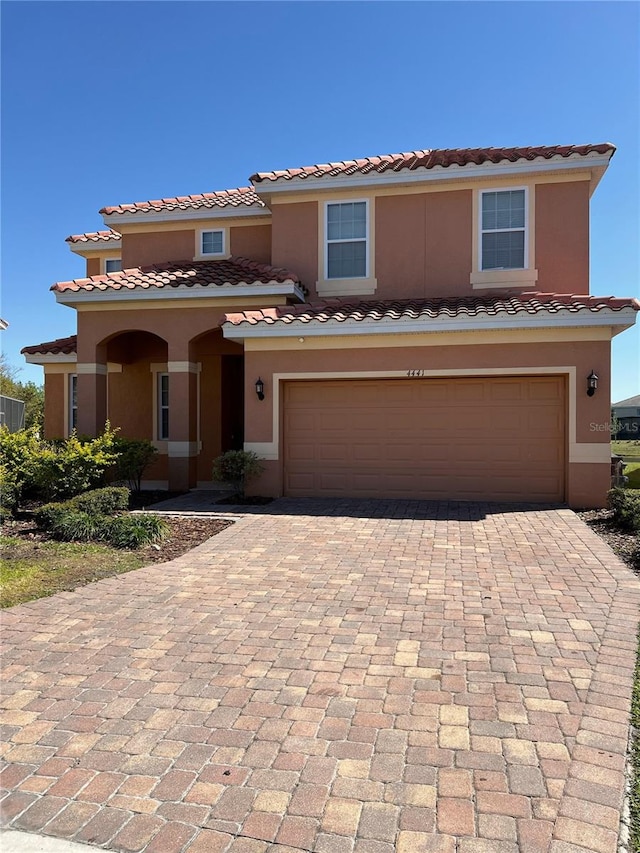 view of front of house with decorative driveway, an attached garage, and stucco siding