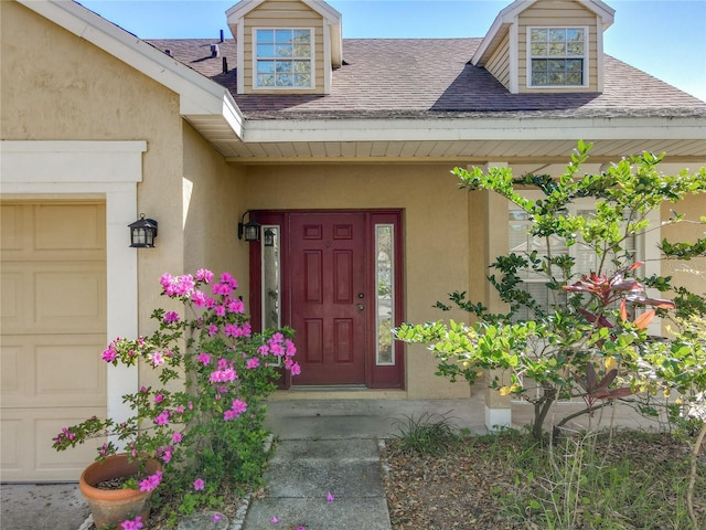 property entrance featuring an attached garage, roof with shingles, and stucco siding