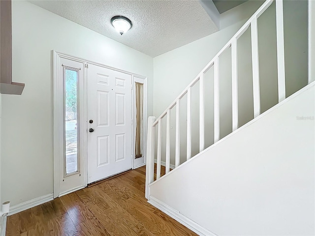 entrance foyer with wood finished floors, baseboards, and a textured ceiling