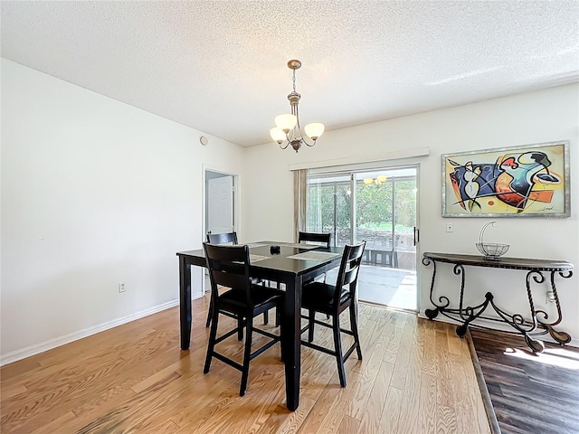 dining space with baseboards, a textured ceiling, an inviting chandelier, and wood finished floors