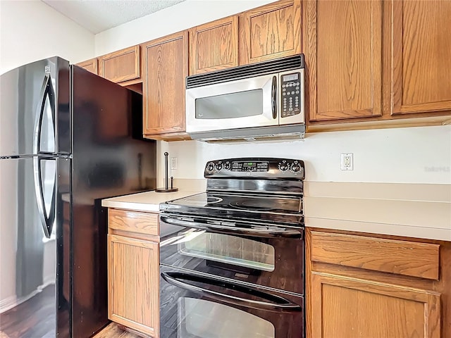 kitchen with stainless steel microwave, electric range, light countertops, and freestanding refrigerator