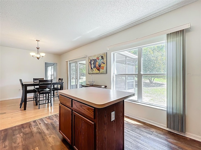 kitchen with a notable chandelier, a textured ceiling, light countertops, dark wood-style flooring, and hanging light fixtures