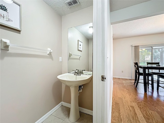 bathroom with visible vents, baseboards, a textured ceiling, and wood finished floors