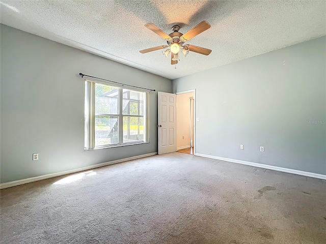 carpeted empty room featuring baseboards, a textured ceiling, and a ceiling fan