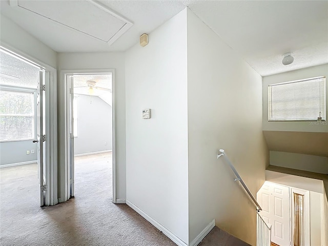 hallway with baseboards, an upstairs landing, and carpet