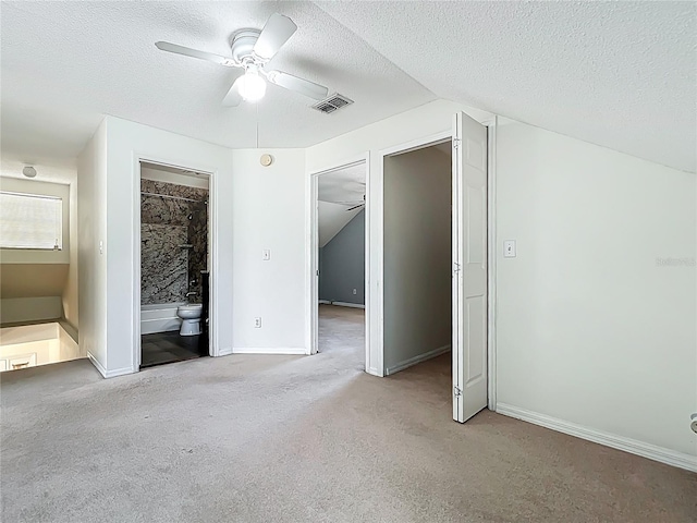 unfurnished bedroom with visible vents, baseboards, vaulted ceiling, carpet floors, and a textured ceiling